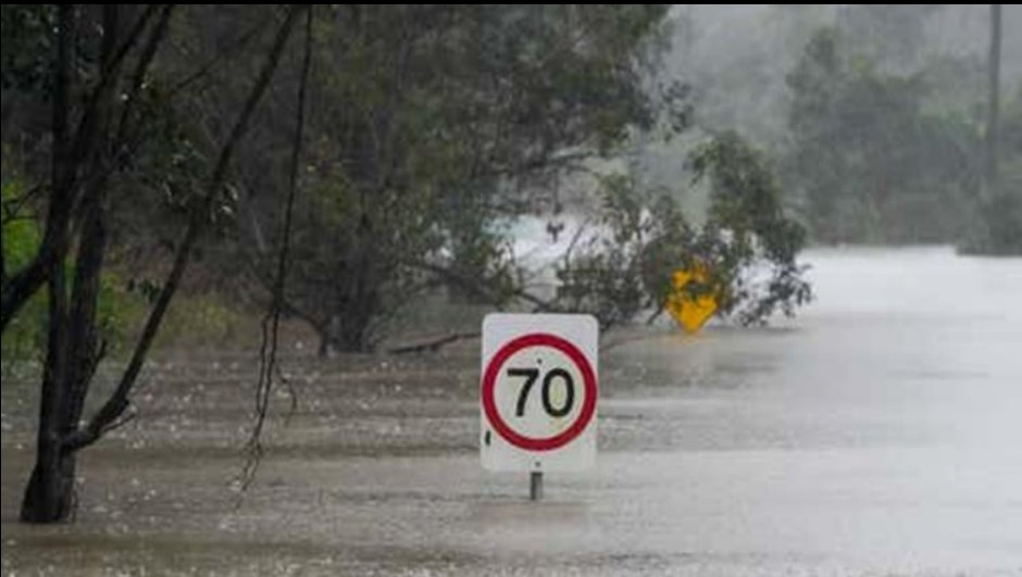 Rua alagada com placa de trânsito semissubmersa