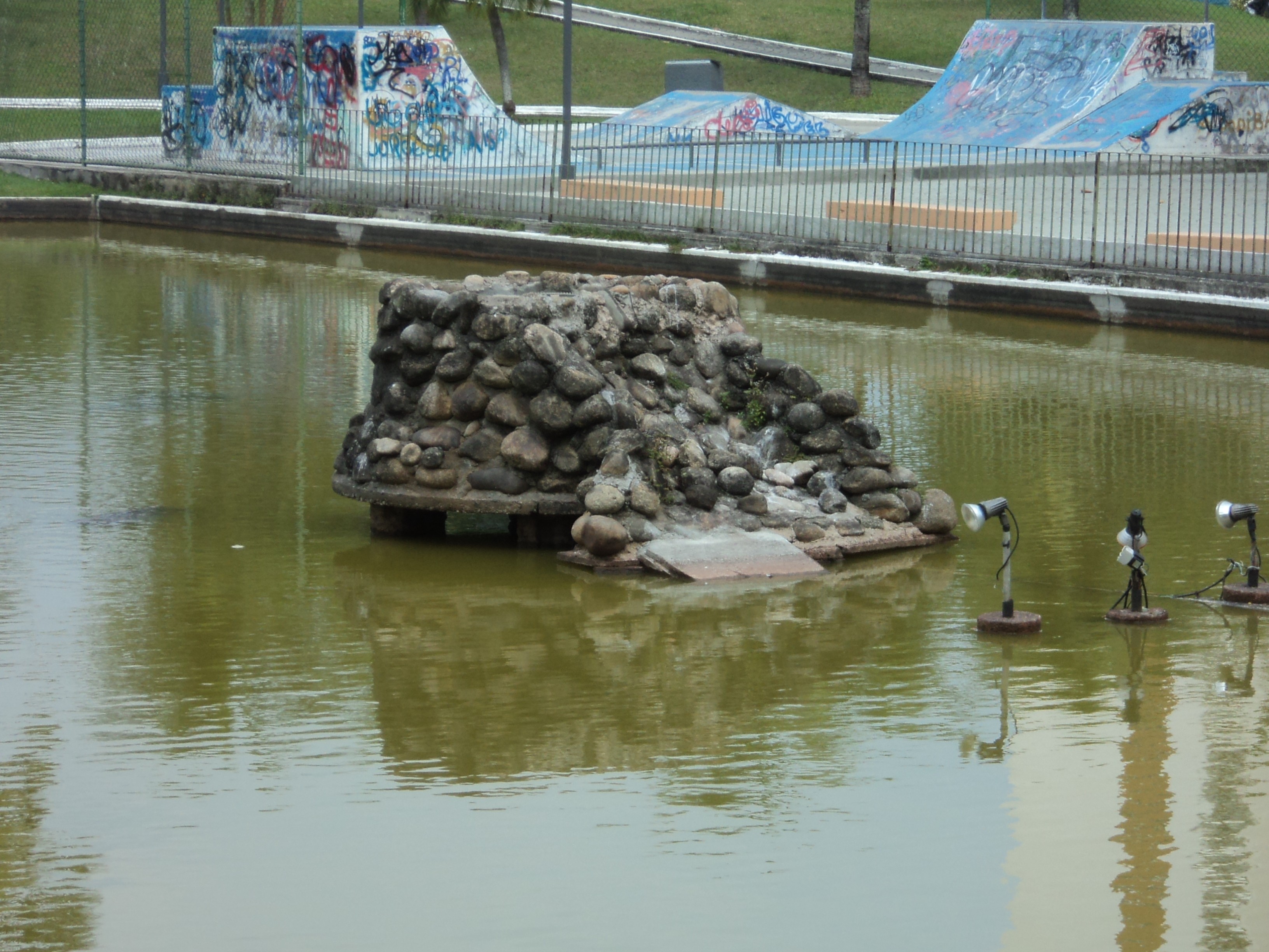Rocha no meio do lago com pista de skate ao fundo